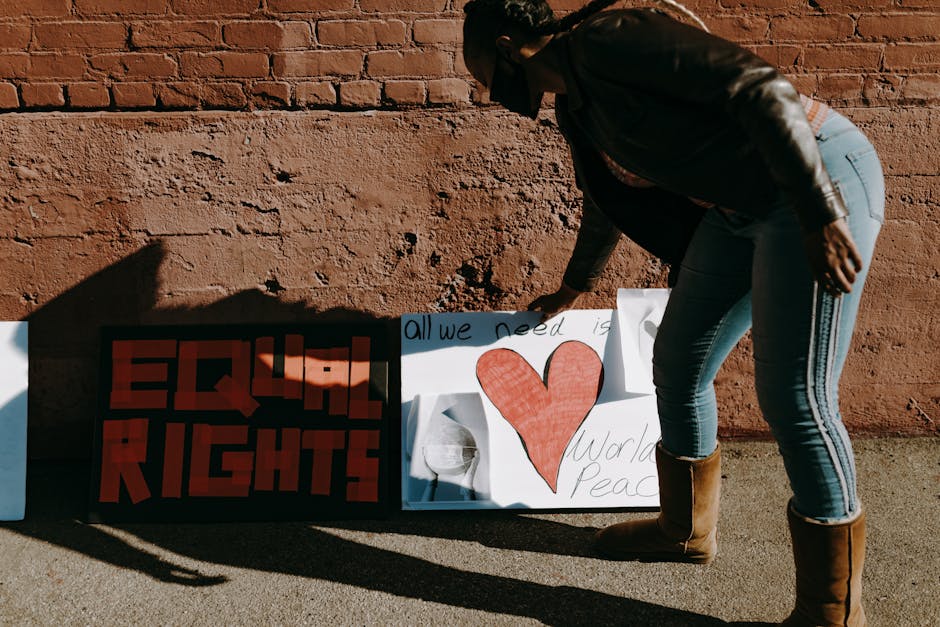 A woman organizing protest signs for equal rights and world peace on a sunny day.